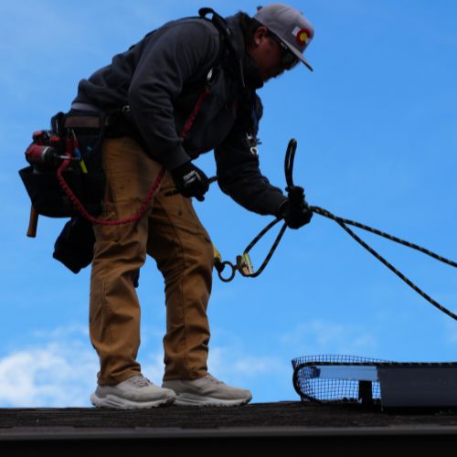 Team member on roof with safety harness installing solar panels by Elite Solar Solutions in Denver, CO